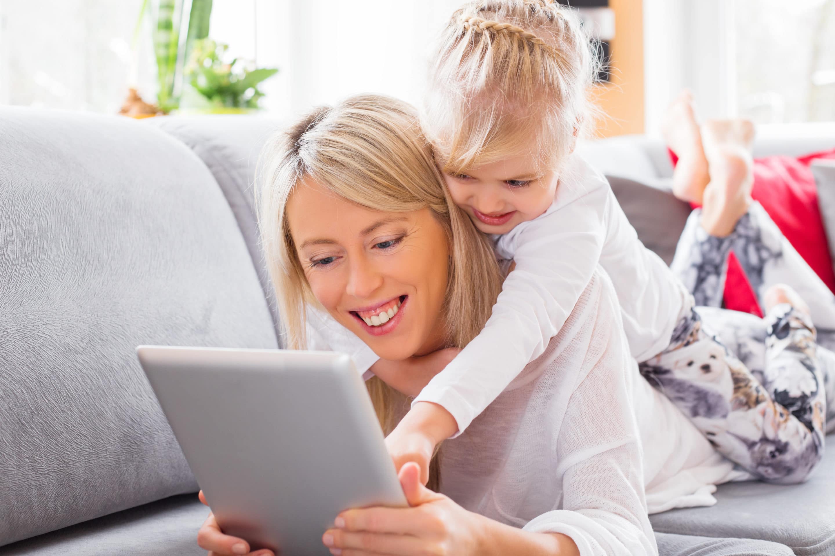 Mati in otrok se smehljata med uporabo iPada, zaščitenega z omrežjem VPN.