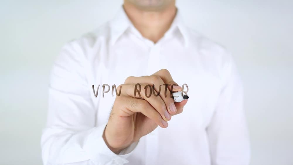 'VPN Router' written on transparent pane with a dry erase marker by man in white shirt